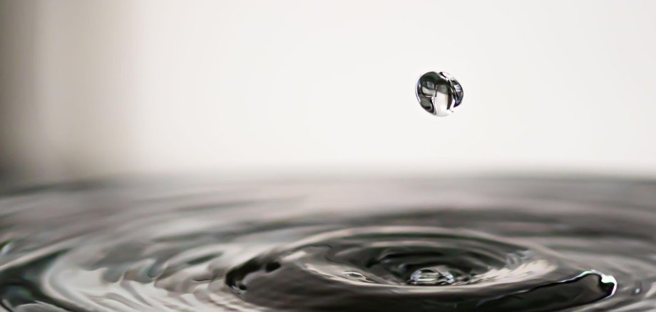 Wasser Einzelner fallender Wassertropfen über einer Wasseroberfläche