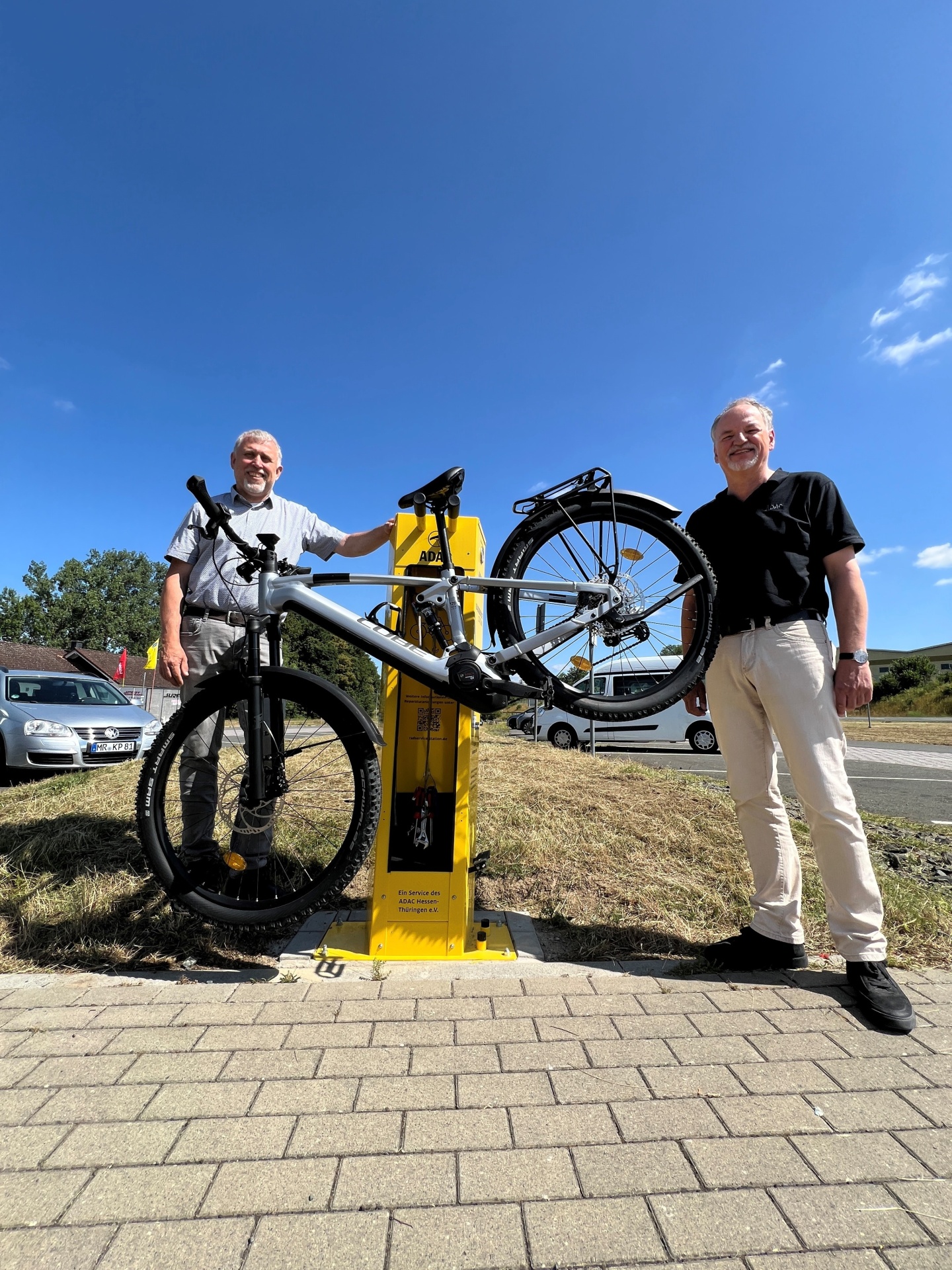 Bürgermeister Marco Herrmann und Wolfgang Herda vom ADAC Hessen-Thüringen stehen neben der Radservice-Station am Aartalsee