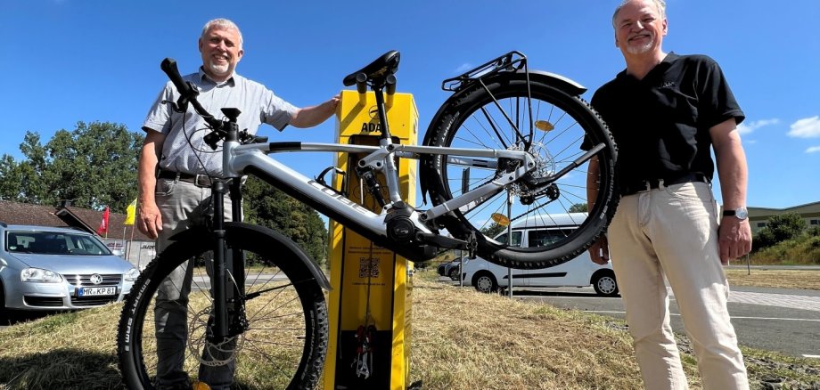 Bürgermeister Marco Herrmann und Wolfgang Herda vom ADAC Hessen-Thüringen stehen neben der Radservice-Station am Aartalsee