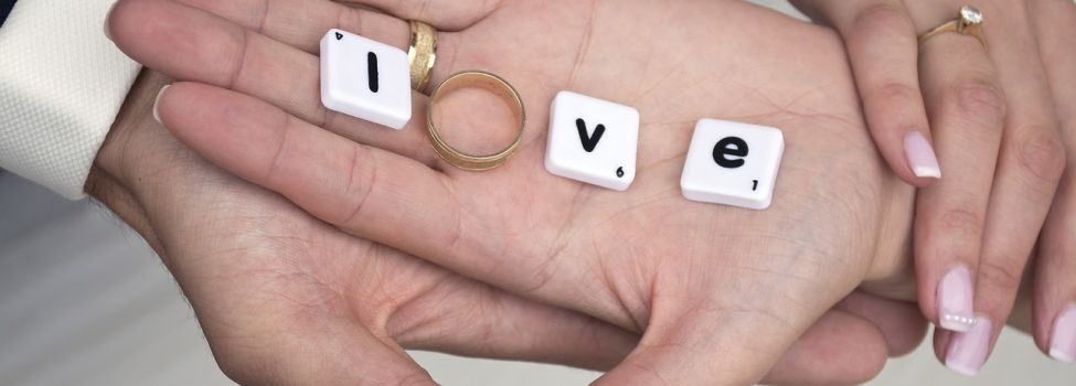 Zwei Hände in denen Scrabblesteine und ein Ring das Wort Love bilden
